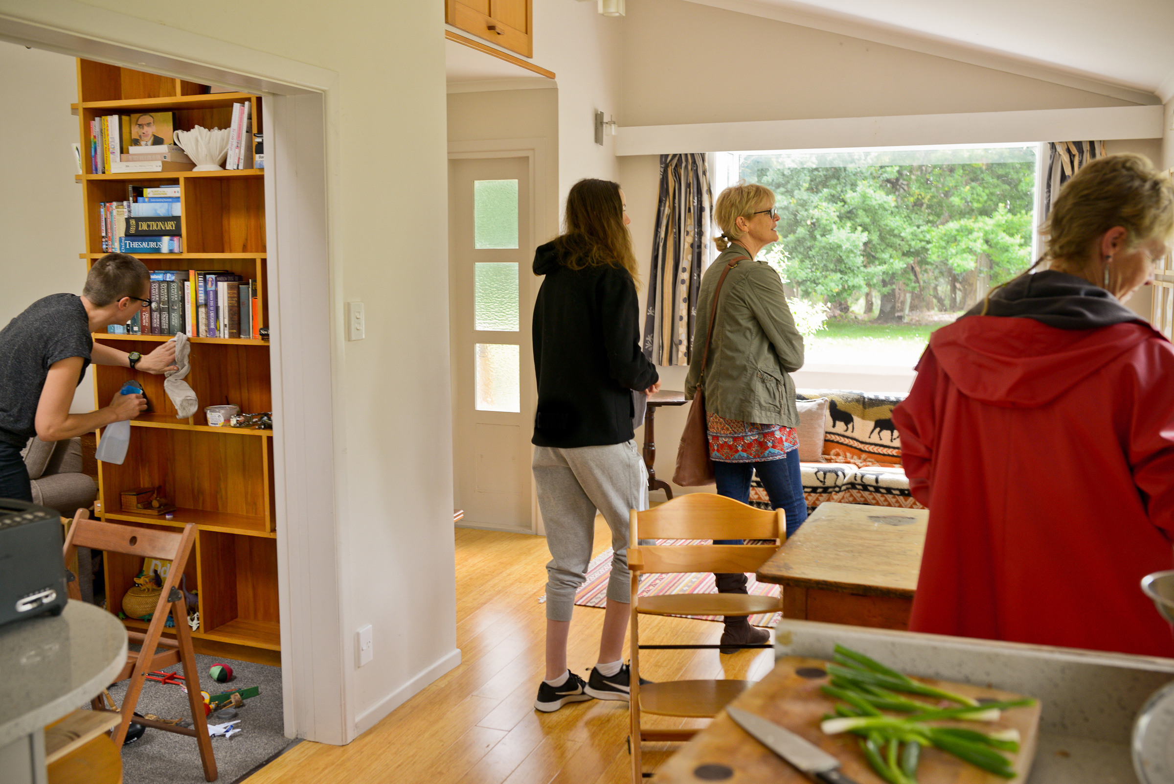 The artist cleans shelves, while visitors examine the living room.