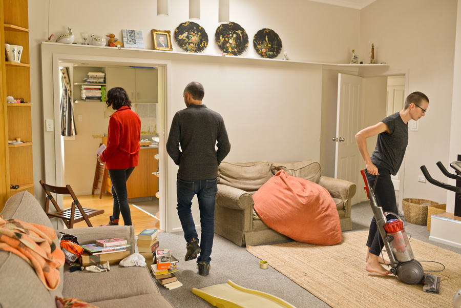 The artist vacuums the lounge as guests walk through.